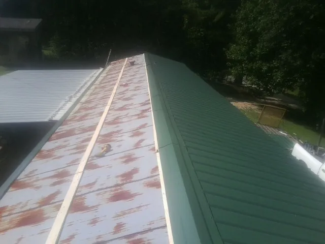 Old rusted panels beside newly installed green metal roofing — Wind Damage Roof Repair by Roofing Brothers in Fishers Island