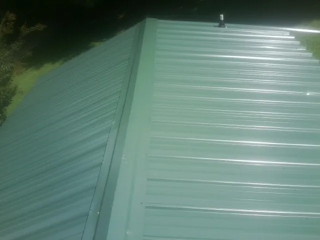 New green metal panels meeting at the ridge of a roof — Flat Roof Repair work by our crew in Fishers Island