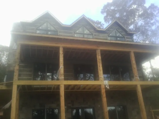 Dormers and porch framing on a large log home under construction — Roof Coating work by our crew in Fishers Island