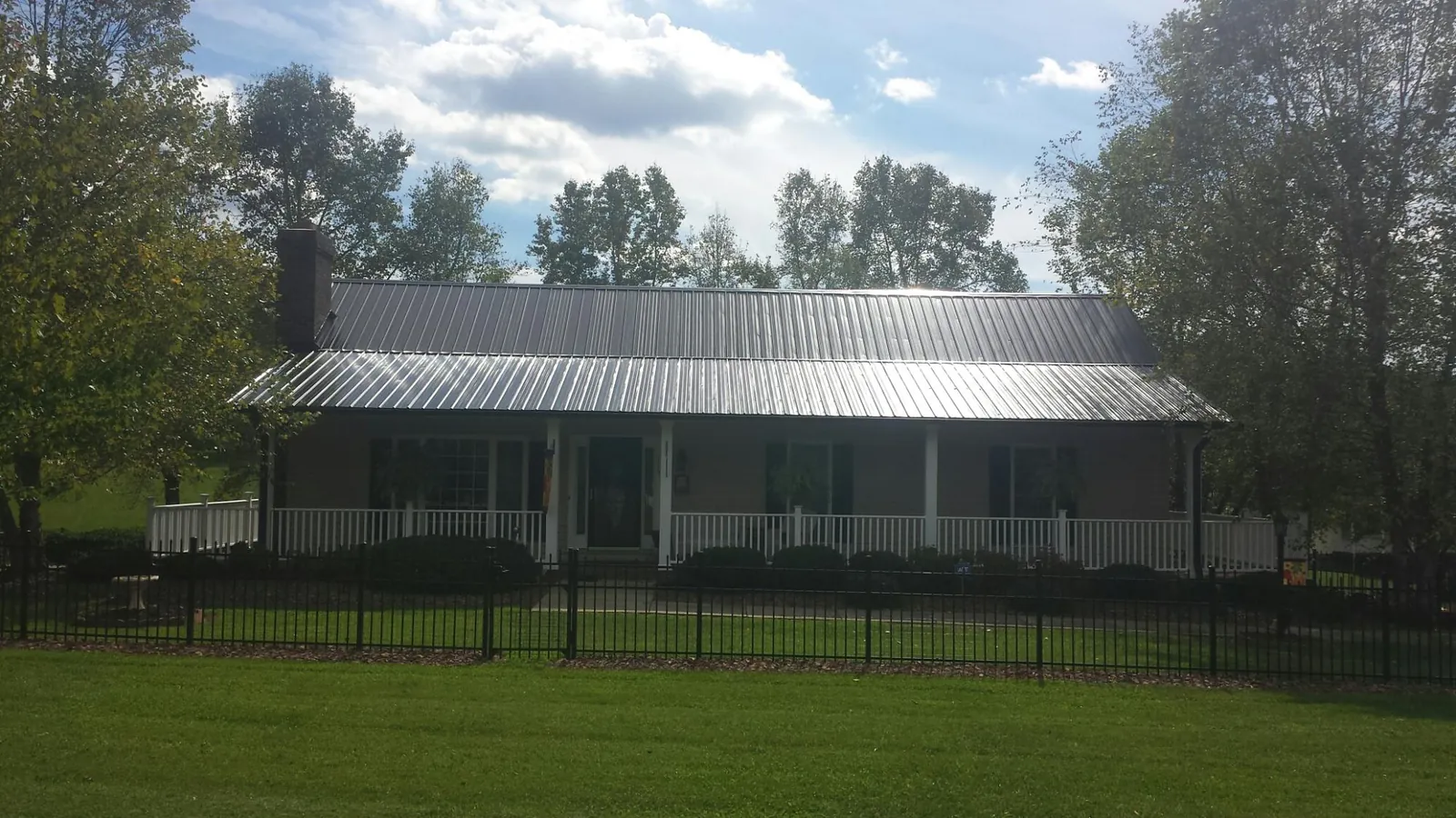 Gray metal roof on a brick ranch with a full width front porch — Gutter Guard Installation work by our crew in Fishers Island