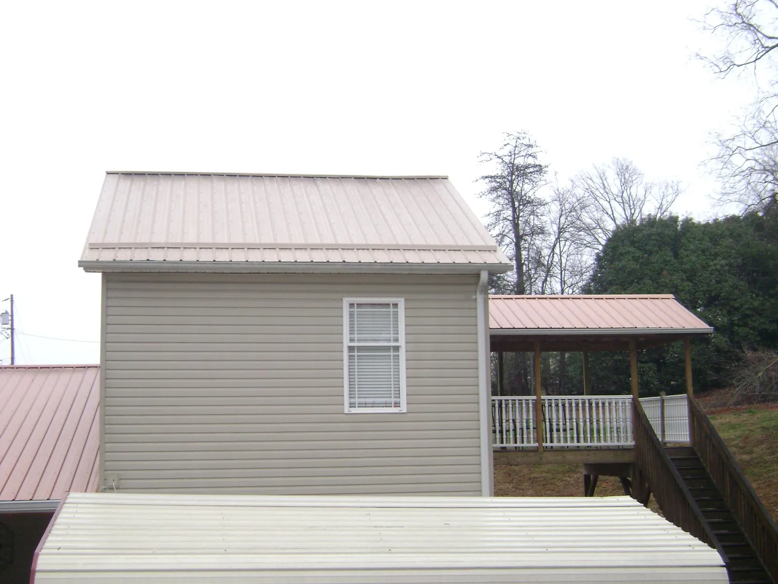 Tan metal roofs on a two story addition and attached porch, from a Roof Replacement job in Fishers Island