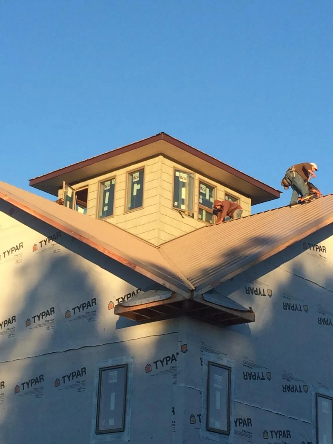 Roofers working around a rooftop cupola on a new metal roof at sunset — Roof Waterproofing in Fishers Island by Roofing Brothers